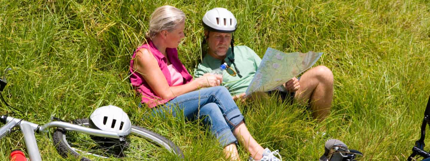 Eine Frau und ein Mann machen eine Pause auf ihrer Radtour und studieren eine Karte.