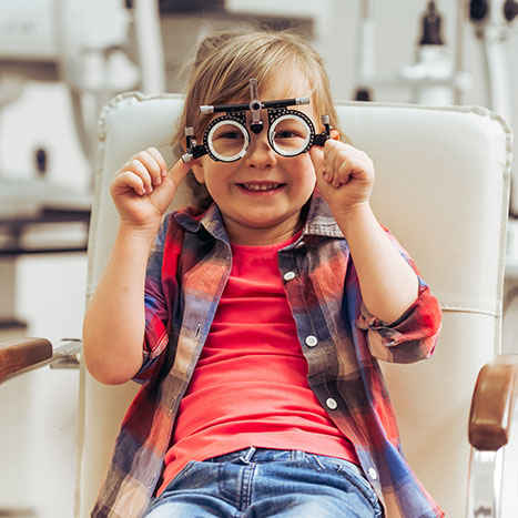 Ein kleines Mädchen sitzt beim Augenarzt und schaut durch ein Dioptrinmessgerät.