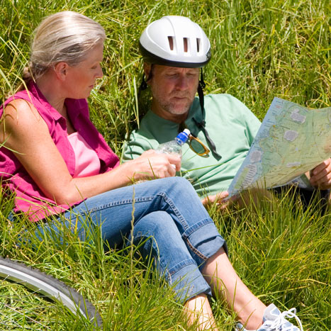 Eine Frau und ein Mann machen eine Pause auf ihrer Radtour und studieren eine Karte.
