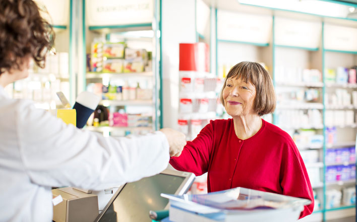 Eine ältere Dame erhält Ein Medikament von einer Apothekerin.