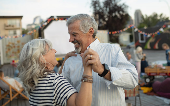 Ein Rentner-Paar tanzt fröhlich zusammen.