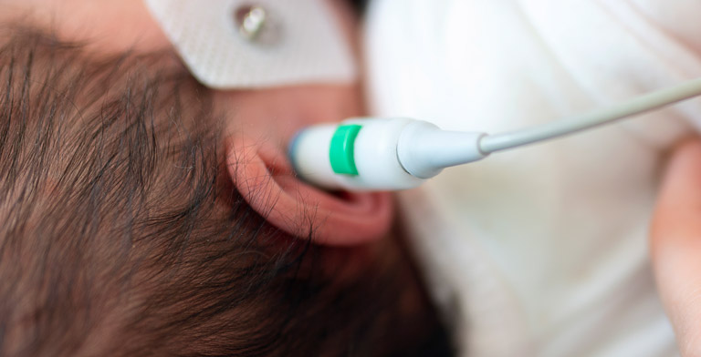 Hörscreening für Neugeborene von der Krankenkasse. Eine Nahaufnahme des Ohres eines Neugeborenen beim Hörscreening.