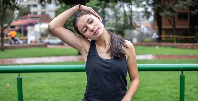 Rückbildungskurs von der Krankenkasse. Eine junge Frau bei einer Dehnübung im Park beim Rückbildungskurs ihrer Krankenkasse.