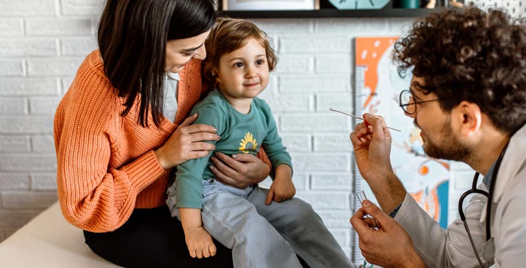Behandlungskosten. Eine Mutter und ihr Kind bei einer Behandlung beim Arzt - sie machen sich keine Sorgen über Behandlungskosten.