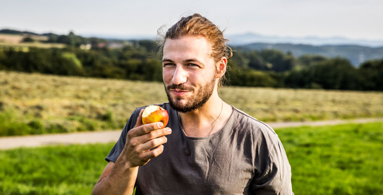Gib mir fünf. Ein Mann beißt in einen Apfel