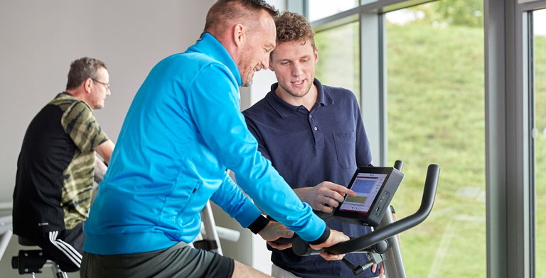 Funktionstraining und Rehasport. Ein Physiotherapeut bei einer Übung mit einem Reha-Patienten beim Rehasport.