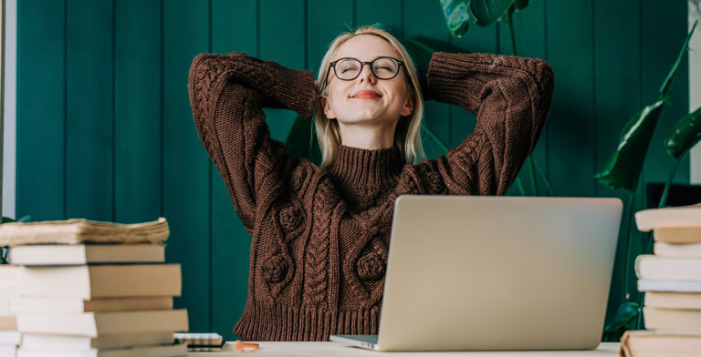 Mit uns können Sie rechnen. Eine Frau sitzt entspannt vor ihrem Laptop, nachdem sie ihre Vorteile berechnet hat.