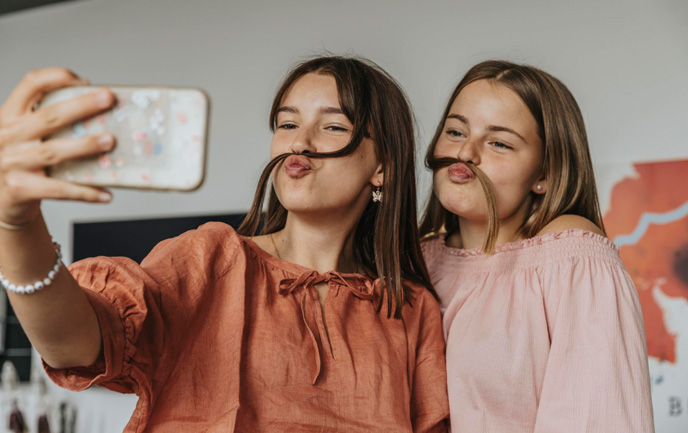 Menstruationszyklus einfach erklärt. Was passiert bei der Periode? Zwei Teenager Mädchen albern rum und freuen sich - ihnen wurde der Menstruationszyklus einfach erklärt