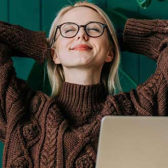 Eine junge Frau sitzt vor dem PC und schaut entspannt und lächelnd mit den Händen hinter dem Kopf nach oben. Eine junge Frau sitzt vor dem PC und schaut entspannt und lächelnd mit den Händen hinter dem Kopf nach oben.